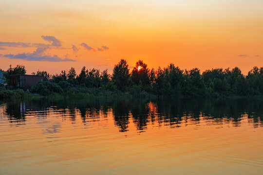 Golden orange sunset over Big Chebachye lake. Vivid gradient sky and ripples on calm water. Scenic background with symmetry reflection evening sky. Burabay National Nature Park Travel destination.