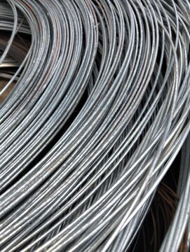 High-resolution close-up of galvanized steel wire coils stacked together, showcasing metallic texture and curved patterns.