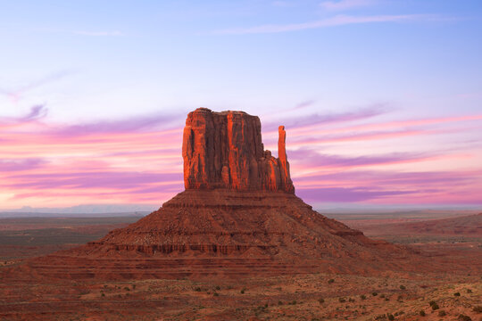 Monument Valley Butte Silhouette at Sunrise with Desert Mist and Vibrant Dawn Sky, Arizona, Utah, US