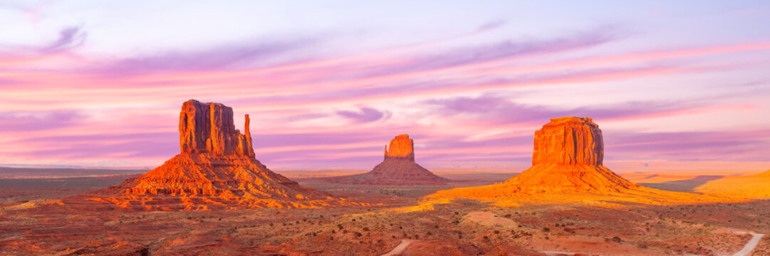 Monument Valley Butte Silhouette at Sunrise with Desert Mist and Vibrant Dawn Sky, Arizona, Utah, US