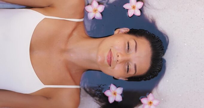 Serene Woman In White Swimsuit Relaxing In Spa Bath With Floating Flowers