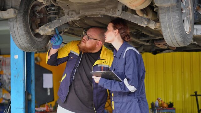 Team of mechanics working together to inspect and maintain a vehicle in an auto repair shop