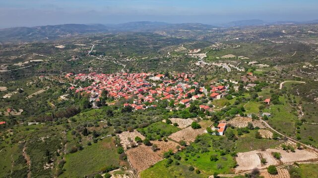 Wide aerial view of Omodos village in the Troodos Mountains, Cyprus. Traditional houses, rolling hills and rural scenery create a scenic mountain panorama.
