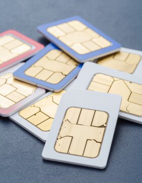 Pile of colorful SIM cards with gold contacts on a dark background for mobile communication and connectivity