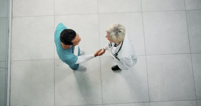 Handshake, above and doctor with nurse in hospital with medical deal, agreement or partnership. Collaboration, people and healthcare employees shaking hands for support, service or contract in clinic
