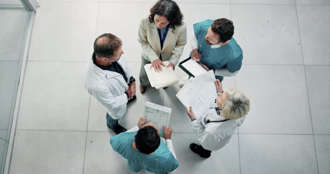 Above, nurse and doctors in meeting with document, patient charts and planning for treatment. People, team and talk in hospital with paperwork, medical records and case study for healthcare services