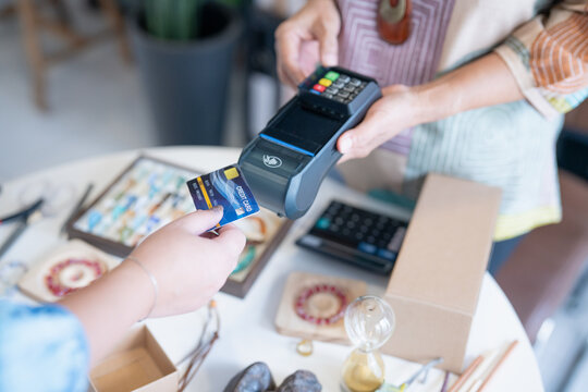 woman tapping credit card on EDC terminal for secure cashless payment in handmade shop using contactless card payment cashless society financial technology