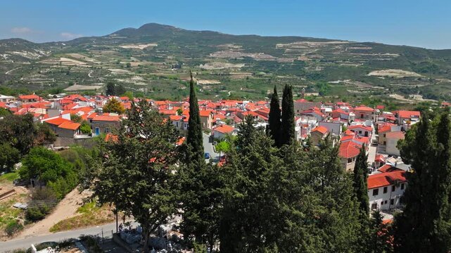 Drone view of Omodos village in Cyprus. Church towers, red rooftops and mountain hills create a charming traditional Cypriot landscape.