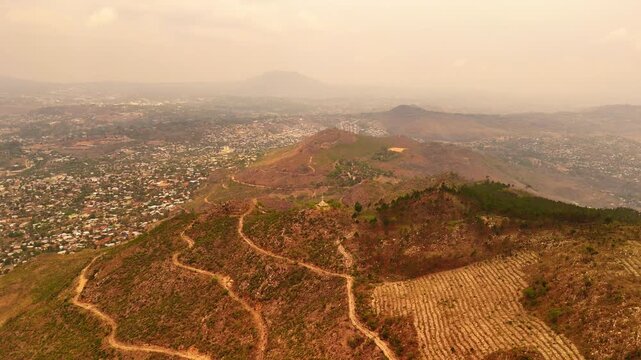 Drone footage flying toward the Way of the Cross on Michiru Mountain while revealing the city of Blantyre under hazy skies.