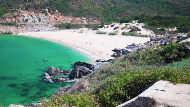 A group of people spend time at a beach in Dak Lak, Vietnam. They walk on the sand, swim in the water, and connect with nature under the sun.