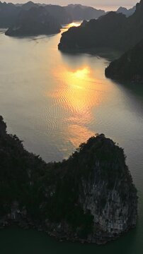 Vertical Aerial View of Golden Hour Sunset Glow Between Karst Peaks in Ha Long Bay Vietnam Landscape