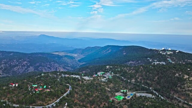 Wide aerial view from Mount Olympus in Cyprus. Blue mountain ranges, deep valleys and forested hills create a dramatic Troodos panorama.