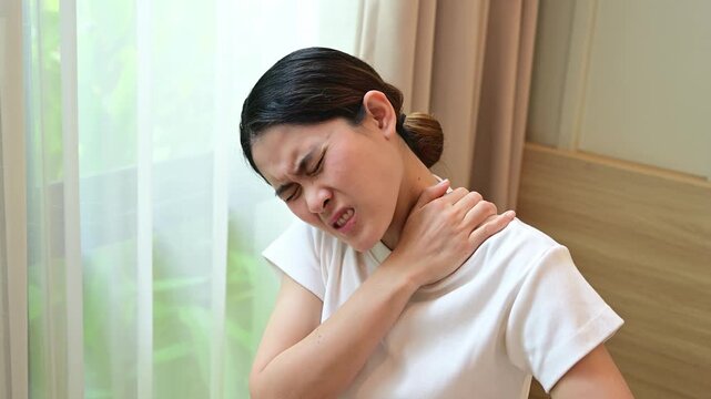 Asian woman having shoulder and neck pain from working longtime. Shoulder pain is when rotator cuff tendons become inflamed or trapped in your shoulder.