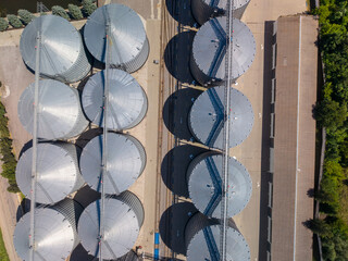 Straight down view of agricultural storage facility showing circular metal silos arranged symmetrically along railway tracks. © Pasha