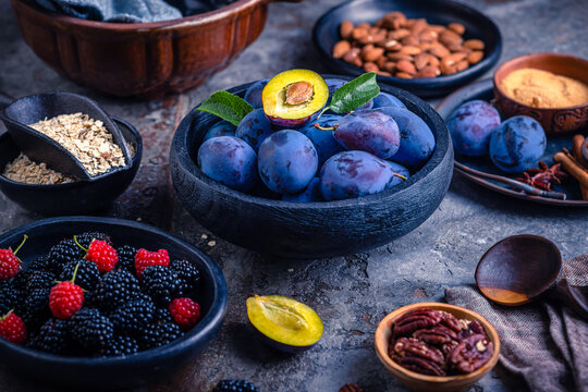 Fresh plums and berries arranged with nuts and oats for a healthy breakfast