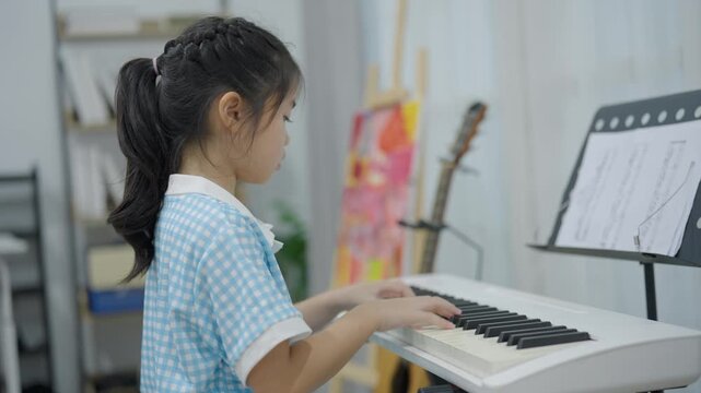 Young girl practicing piano at home in casual outfit focusing on music sheet and keyboard in cozy room environment