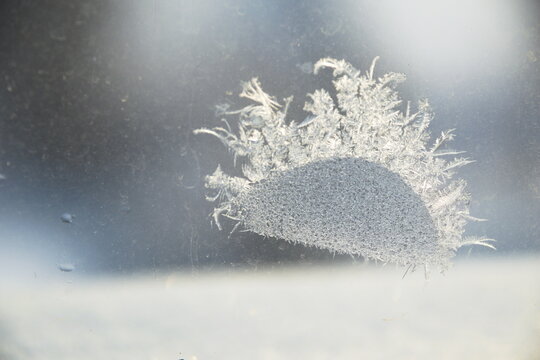A large delicate snowflake formed on a window surface, showcasing intricate ice patterns and natural winter beauty. Close-up view of frost texture with a soft background, perfect for seasonal and atmo