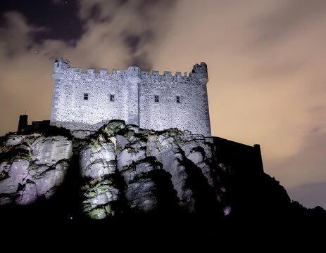 Ancient stone castle ruins under dramatic sky silhouette.