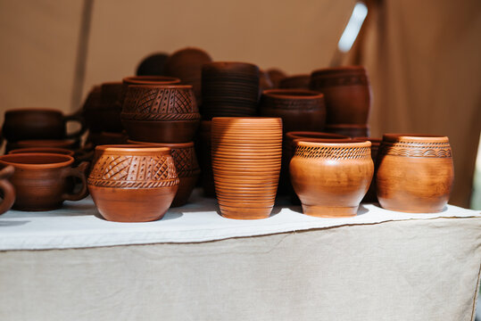 Various handcrafted pottery pieces are displayed on a table at a festival reflecting elements of medieval culture
