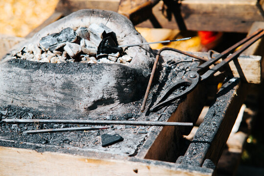 A medieval blacksmith station is set up during a festival, showcasing tools and materials used for crafting