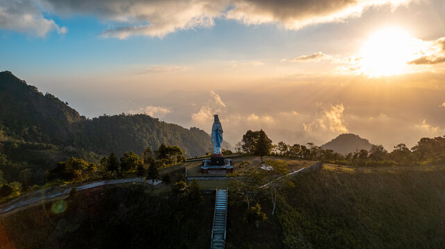 Aerial view of the Virgin Mary statue standing on a hilltop overlooking the lush mountainous landscape of Bajawa, Nusa Tenggara Timur, Indonesia.