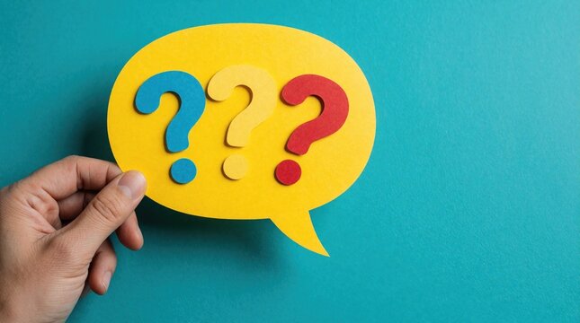Hand holds yellow speech bubble with three colorful question marks inside on teal background. Symbolizes asking questions finding answers support or help desk queries.