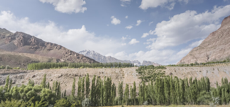 Mountain landscape in the Pamir Mountains of Tajikistan, with rocky slopes and green vegetation, in sunny weather in the Tien Shan Mountains