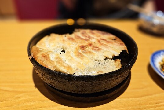 Delicious Japanese tetsu nabe gyoza dumplings in a hot iron pan for professional food and dining concept background.