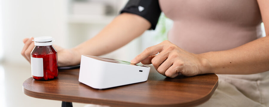 Woman checking her blood pressure at home with a digital  blood pressure measuring device.