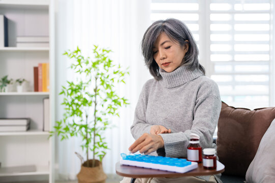woman  putting daily medicine  into a monthly pill box for daily medication routine, organization tablets with pill box. Home health care.