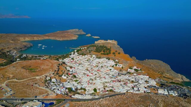 Scenic aerial drone view of the ancient acropolis, white town, and blue sea in Lindos, Rhodes, Greece