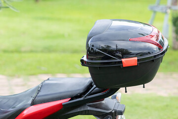 Fototapeta premium Motorcycle with black storage box and red accents on grassy roadside
