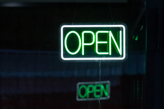 Vibrant green illuminated sign signals store is open at night