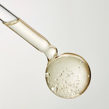 Close-up of a dropper releasing a viscous liquid with tiny bubbles