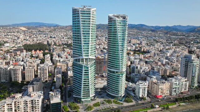 Drone view of Limassol skyscrapers and city centre in Cyprus. Tall towers, urban buildings and mountain backdrop create a modern city panorama.