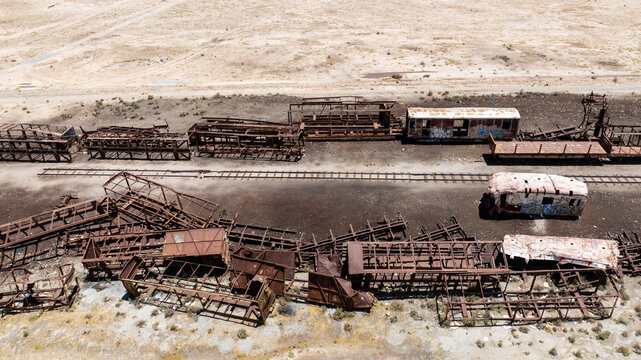 Aerial view of the historic Train Cemetery featuring rusted locomotive skeletons and abandoned railway carriages scattered across the arid desert landscape in Bolivia.
