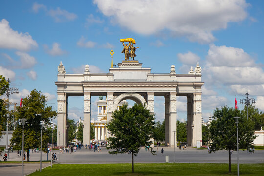 A golden statue of a man and woman holding a large sheaf of wheat, symbolizing Soviet agricultural achievements, atop the VDNKh Pavilion in Moscow, Russia.