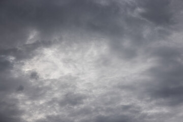 Fototapeta premium Dense, swirling storm clouds dominate the frame in muted grays