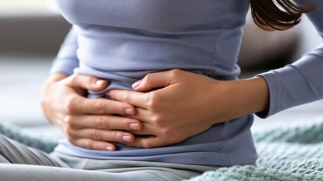 A woman gently holds her stomach, reflecting discomfort and seeking relief.