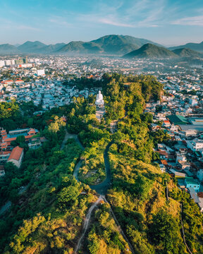 Aerial view of Long Son Pagoda featuring the large white Buddha statue surrounded by lush greenery and urban rooftops in Nha Trang, Khanh Hoa, Vietnam.