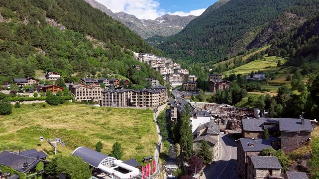 Arinsal village in Andorra nestled in a green mountain valley, featuring alpine architecture, a winding river, cable car station and forested Pyrenees peaks