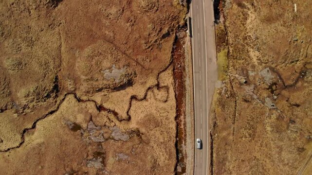 Top down shot of a red car on a remote road through golden moorland, Glencoe.