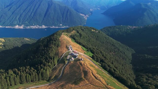Majestic aerial view of a mountain ridge with a small village, overlooking the stunning blue waters of lake como and its surrounding forests