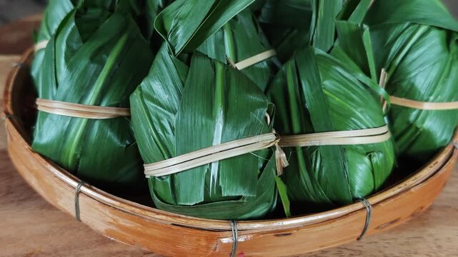 traditional sticky rice dumpling wrapped in green leaves, tied with bamboo string
