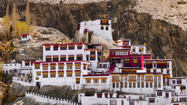 Aerial view of Diskit Monastery, a historic Tibetan Buddhist monastery with white and red buildings nestled against a rugged mountain slope in Diskit, Ladakh, India.