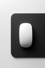 Obraz premium White wireless computer mouse sits on black textured pad. Minimalist top view shows sleek hardware for modern office desk. Simple digital tool provides smooth control for workspace productivity. High