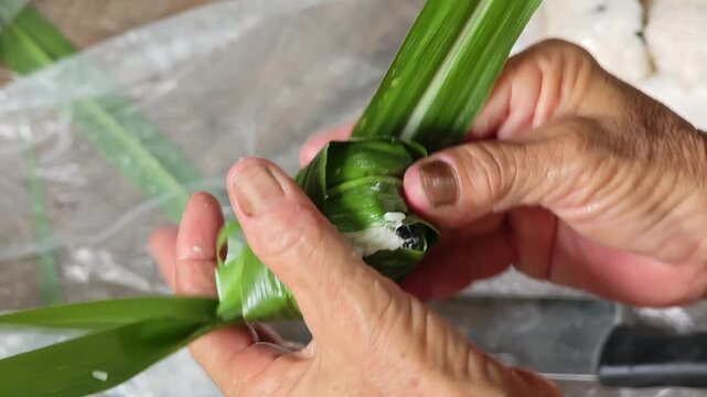 traditional sticky rice dumpling wrapped in green leaves, tied with bamboo string
