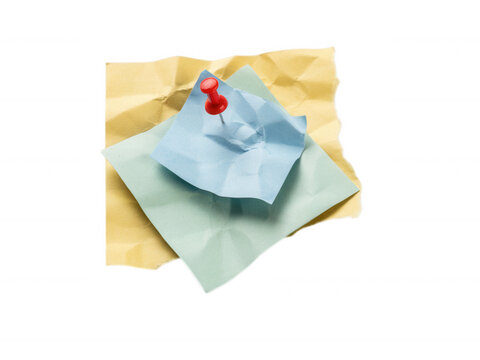 Layered crumpled sticky notes in yellow and blue pinned with a red push pin isolated on transparent background