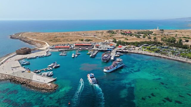Aerial view of Paphos Harbour in Cyprus. Clear turquoise water, marina docks, tour boats and the historic waterfront create a scenic Mediterranean travel panorama