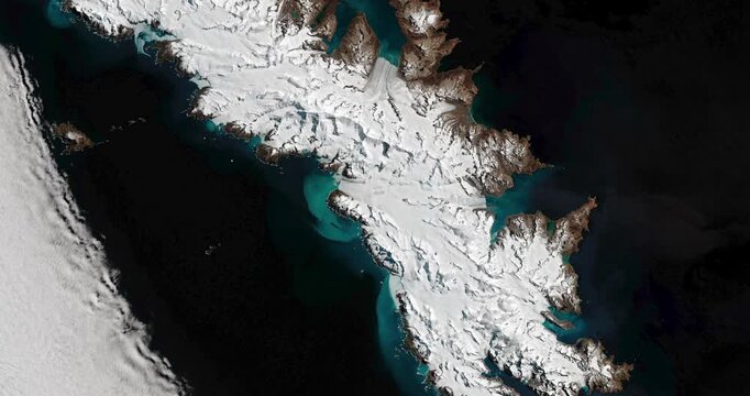 Top shot on South Georgia, island covered with snow and glaciers flowing into ocean. Camera is zooming in. Animation based on image by NASA